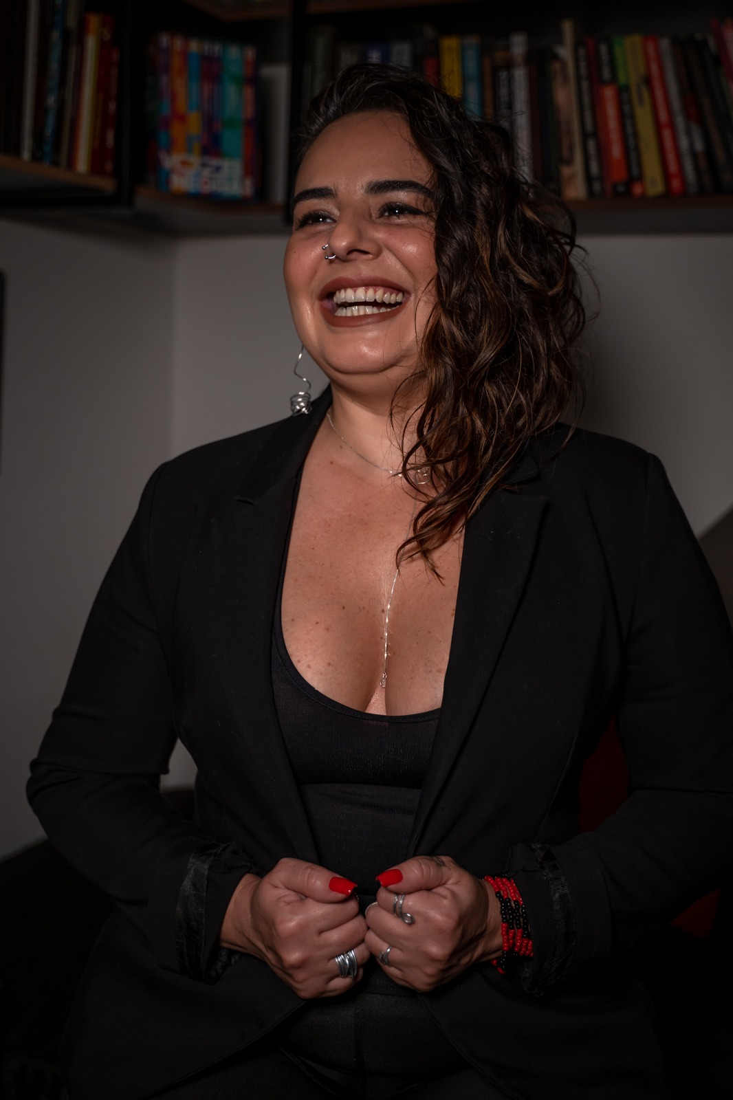 Michele Borges, psicóloga e psicanalista, sorrindo em frente a uma estante de livros